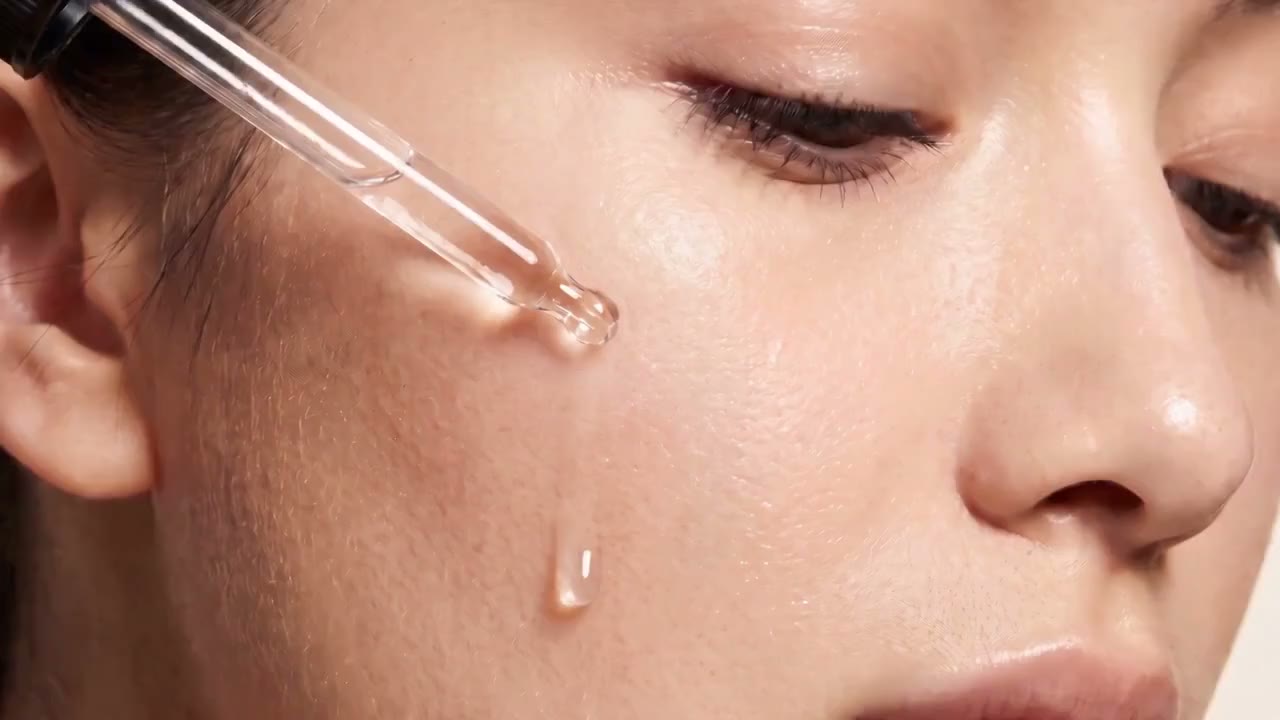 Close-up of skin as a drop of serum is applied to the cheekbone